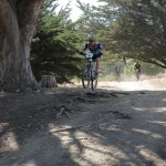 Men's Sport rider taking flight off a root section.